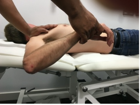 Clinical examination photo assessing internal rotation of the shoulder with the patient lying flat