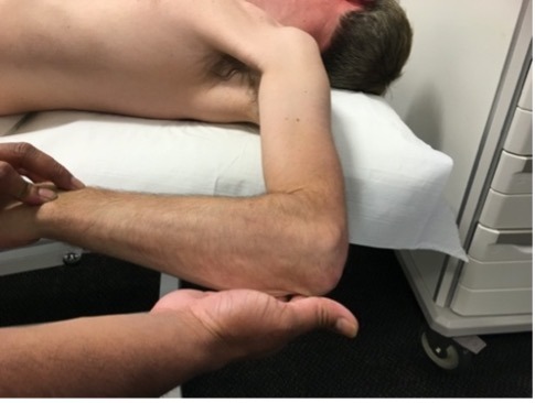 Clinical examination photo testing shoulder internal rotation with the patient lying on their side