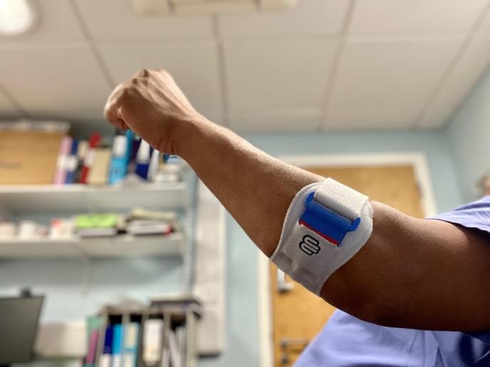 Patient wearing a forearm bracing strap for tennis elbow
